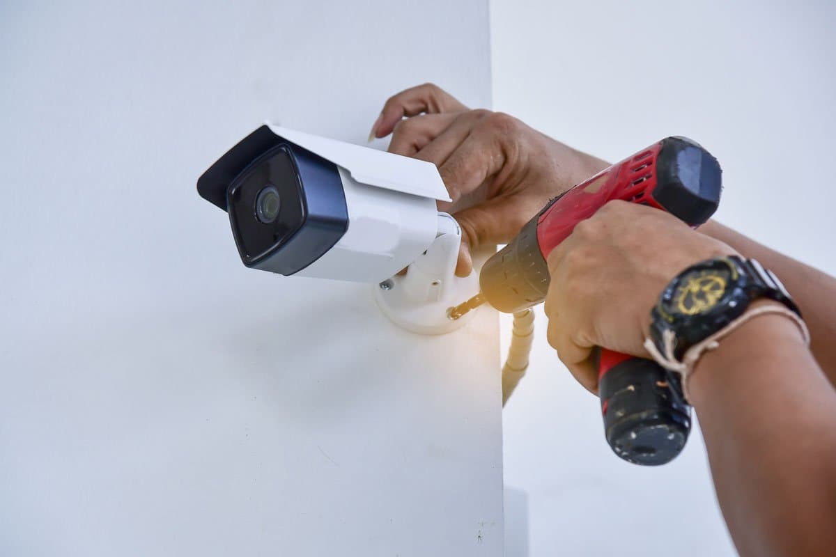 Technician drilling to mount an outdoor security camera