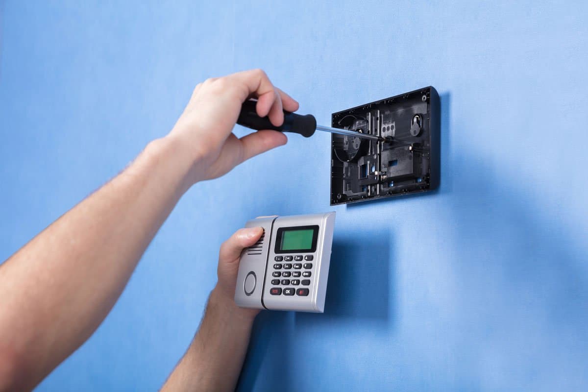 Technician wiring an alarm control panel